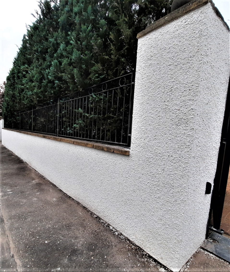 roughcast render repair on white textured garden wall