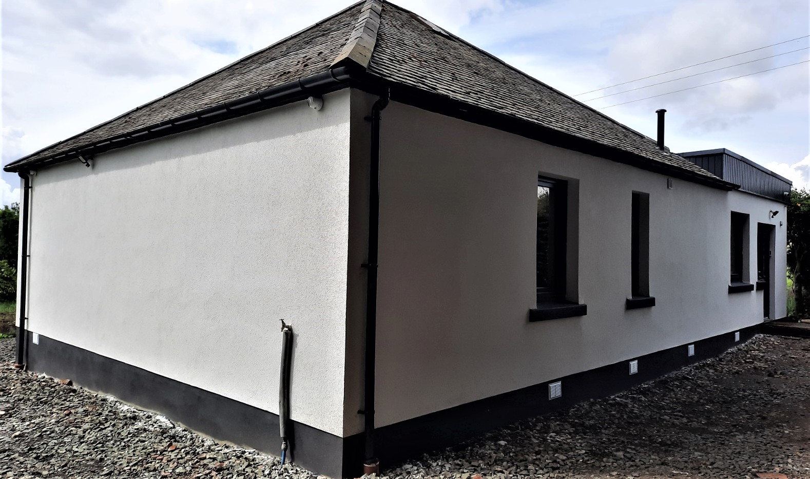 roughcast render repair on gable end wall with dark base