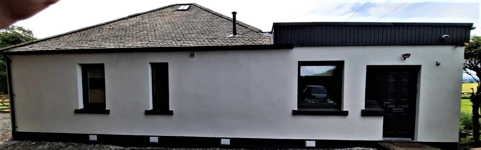 roughcast render Edinburgh on long white wall with black trim