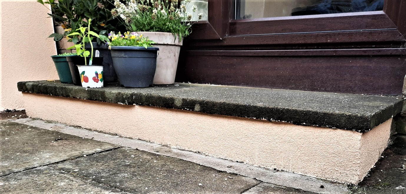 roughcast repair along base of wall beside doorway