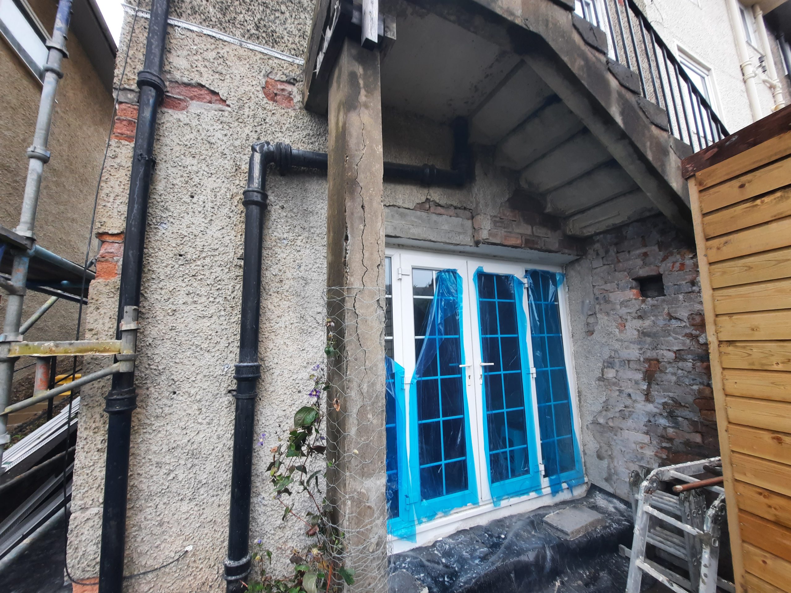 roughcast render repair in progress on wall beside exposed brickwork