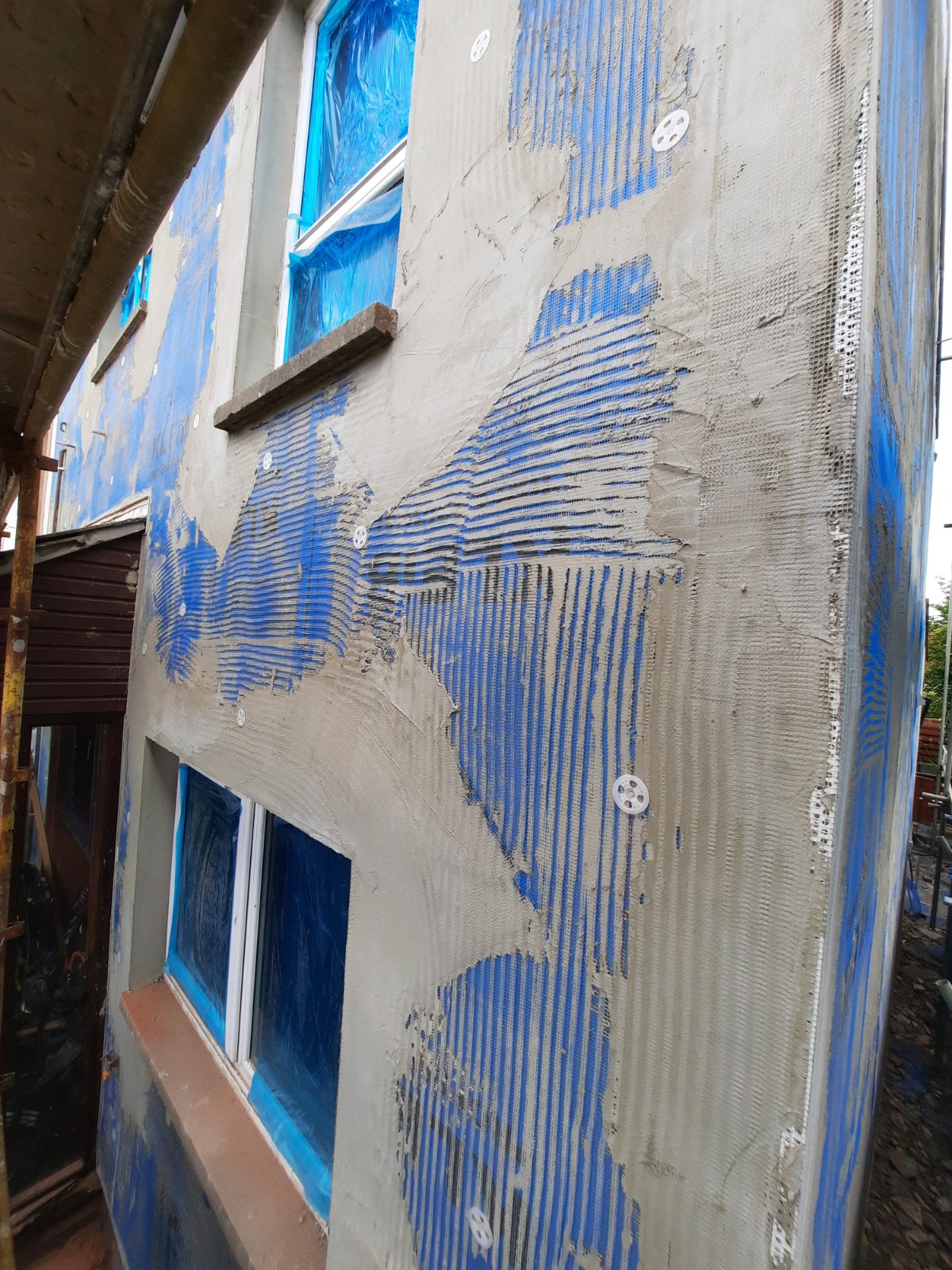 roughcast render repair on upper side elevation beside blue window