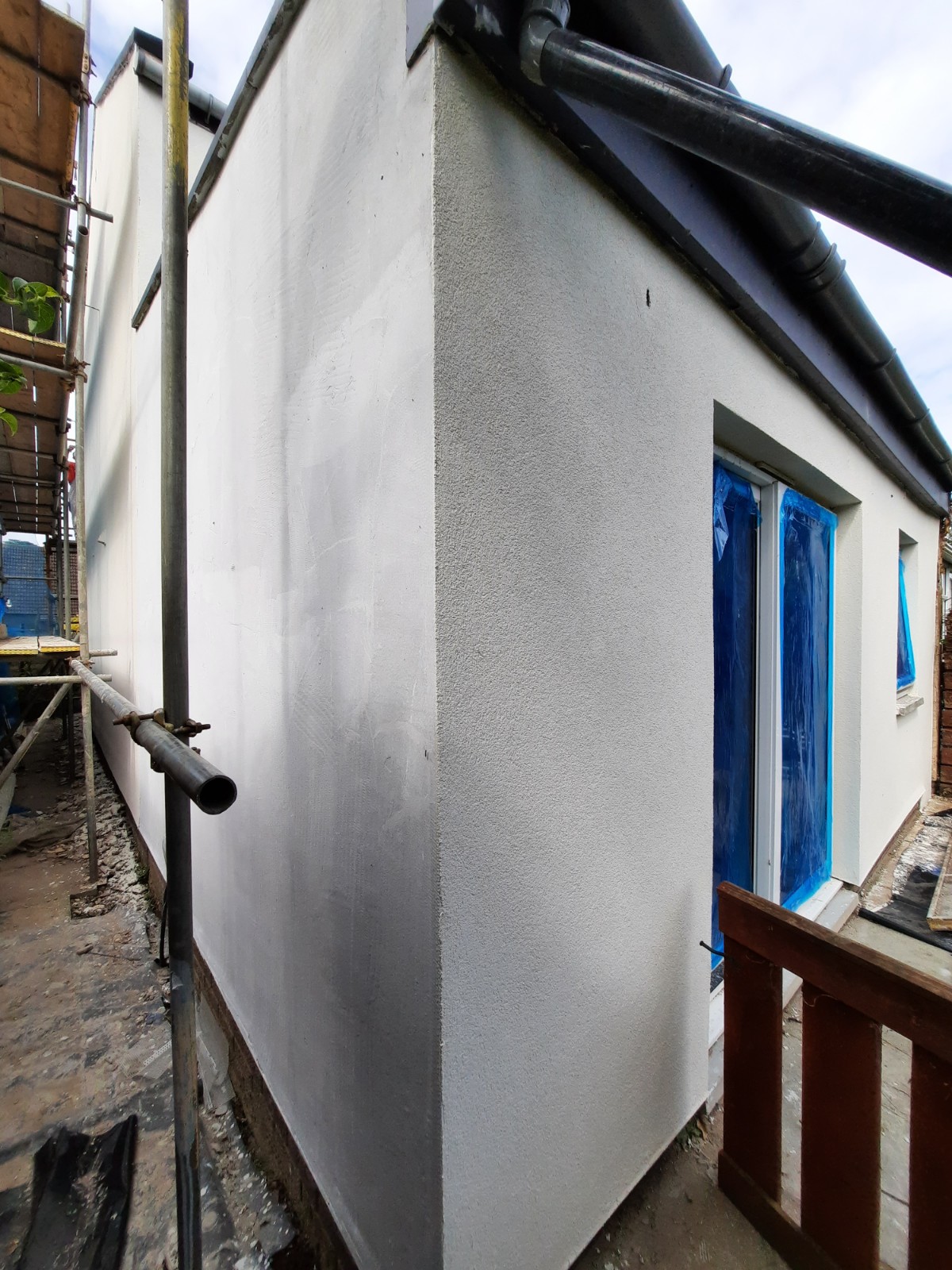 roughcast render repair on fresh white wall beside blue window cover