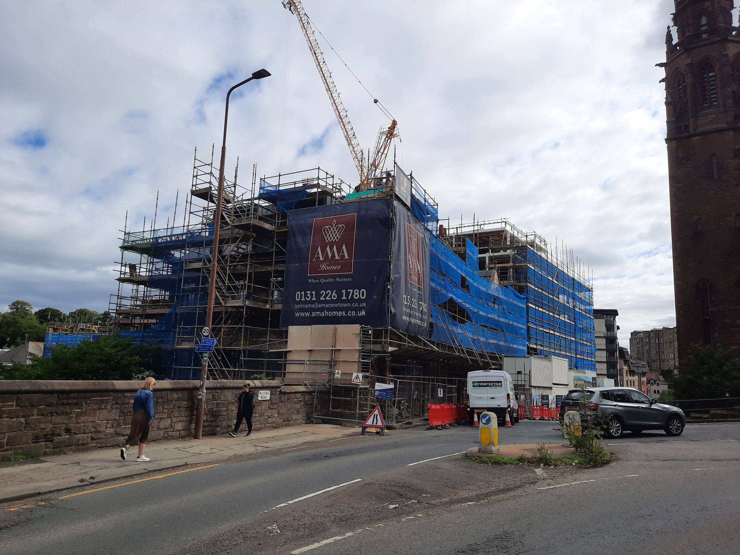roughcast repair on large building covered with blue safety netting