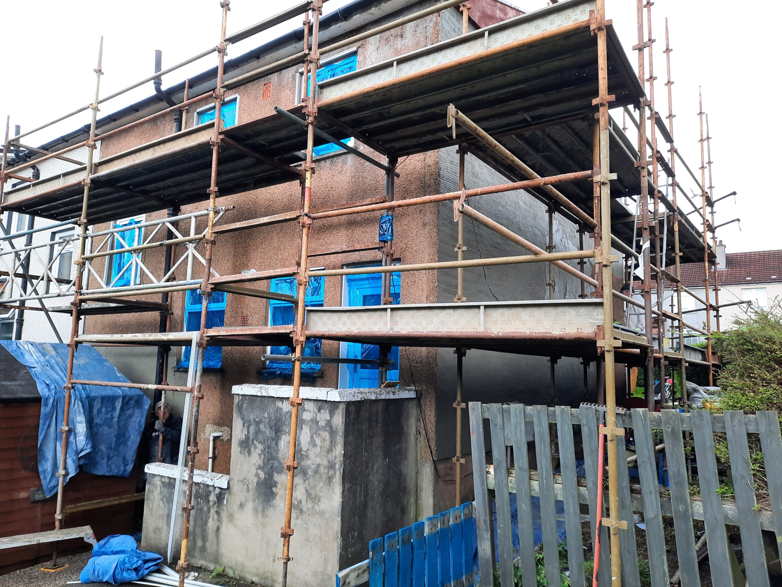 roughcast render repair on upper façade under scaffolding