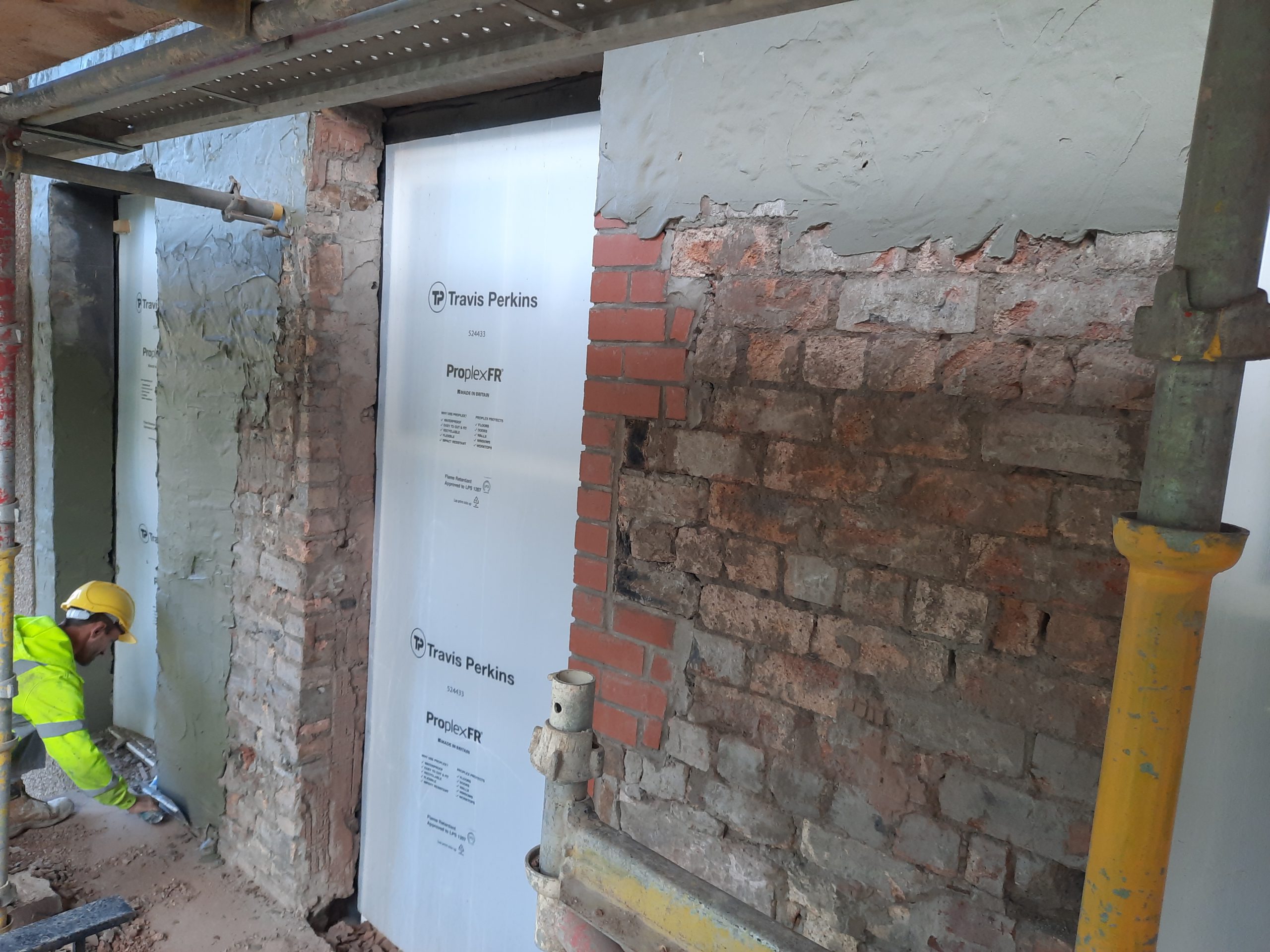 roughcast render repair over exposed brick wall section