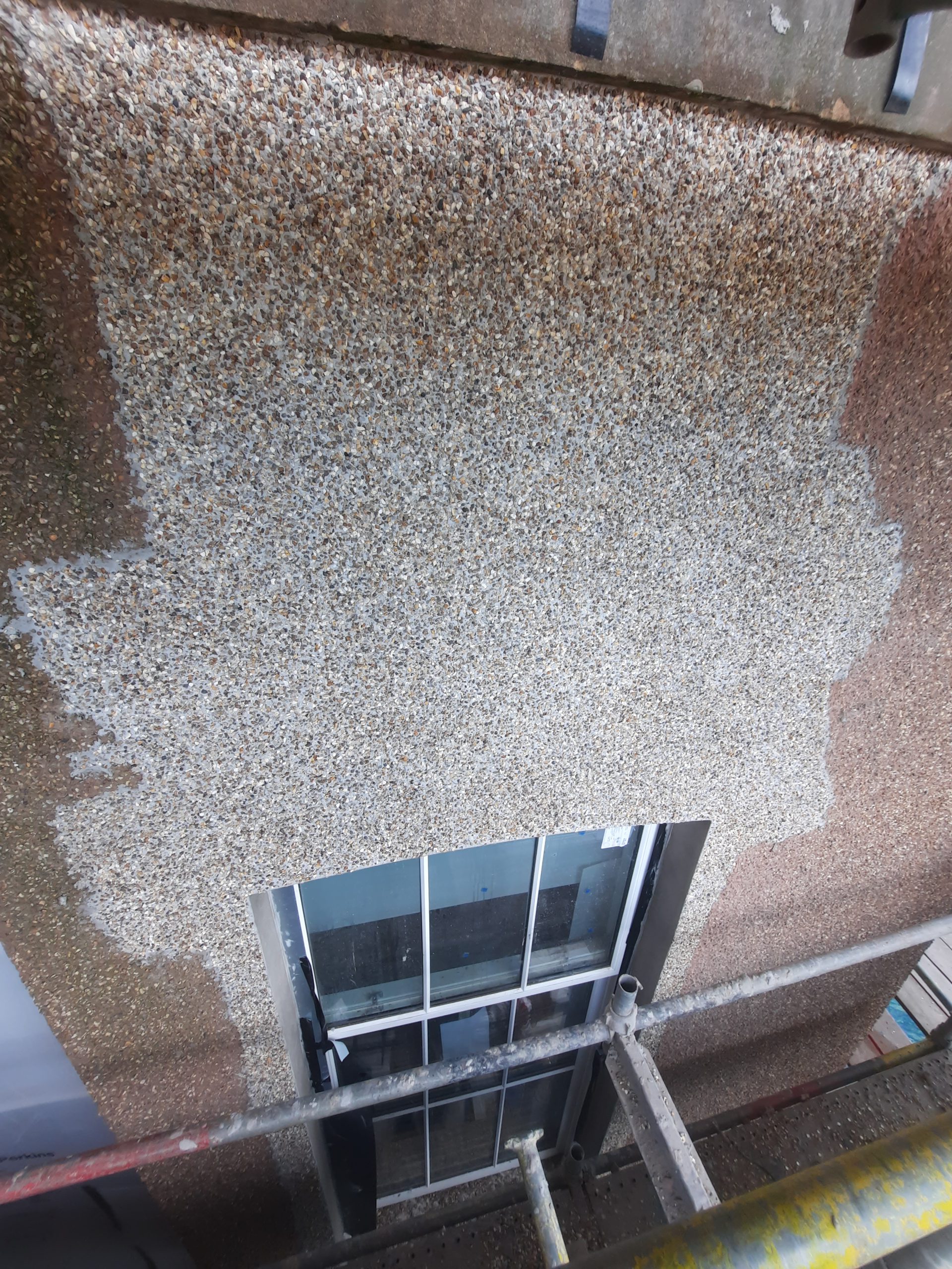roughcast render repair on wall with old coating partially removed