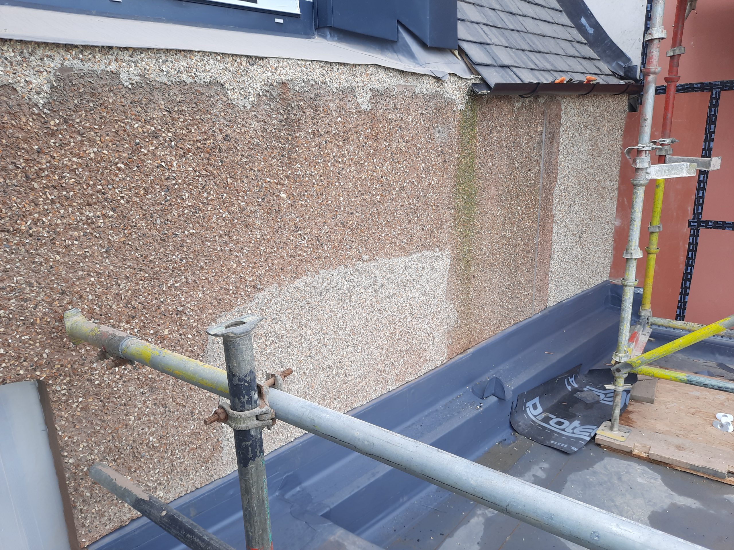 roughcasting Edinburgh on wall with partly removed old pebble dash