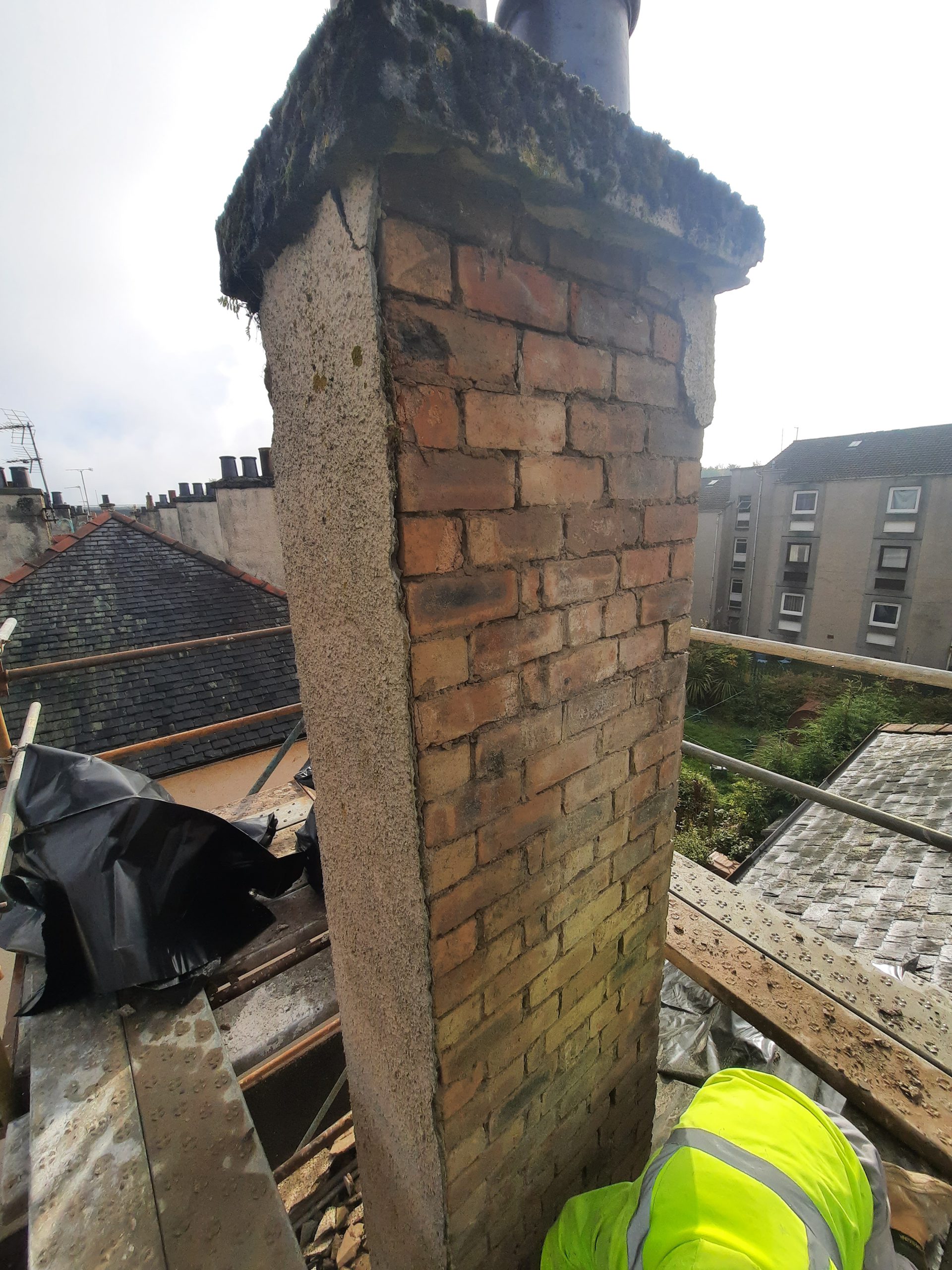 roughcast render repair in progress on rooftop chimney