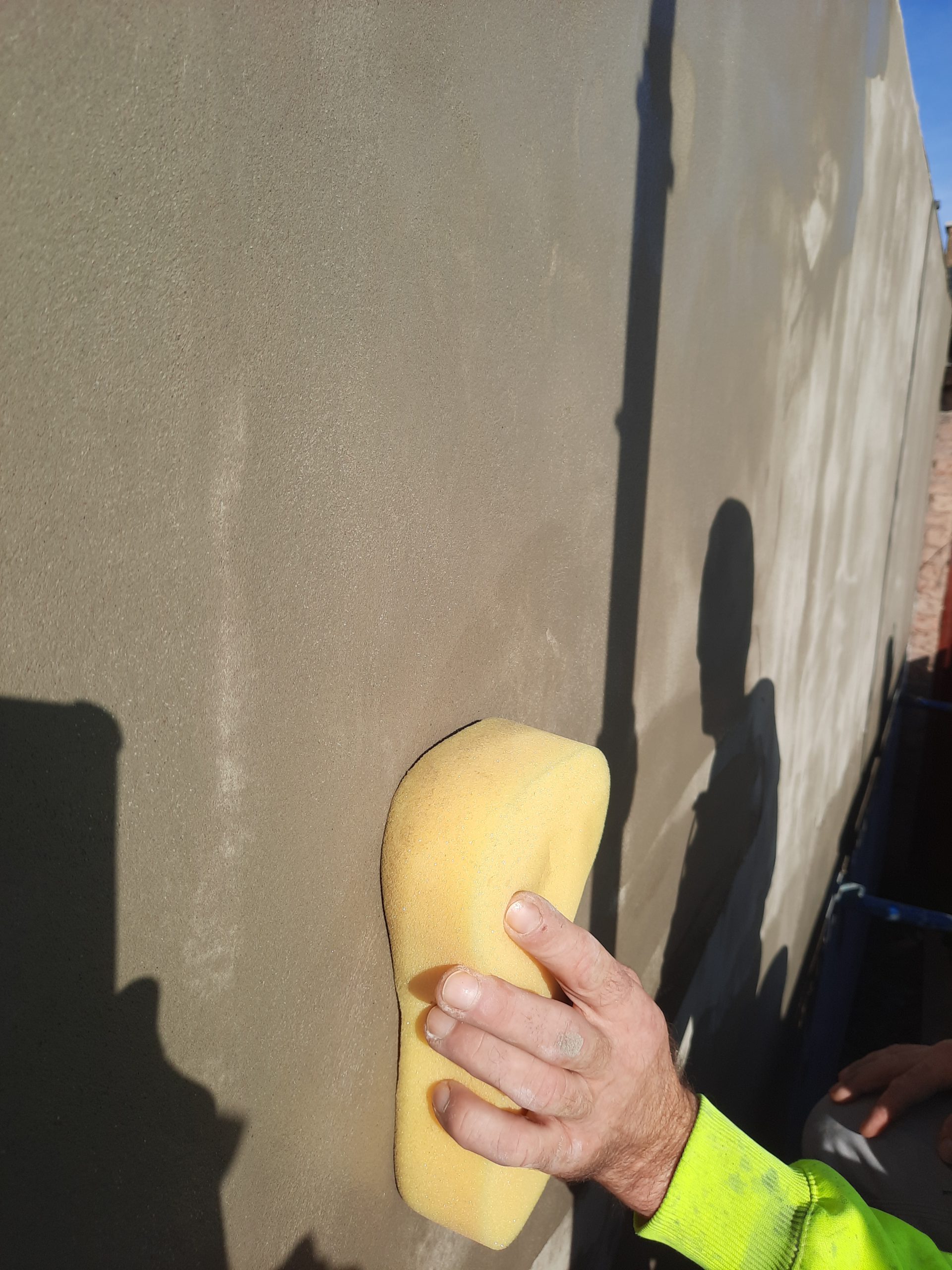 roughcasting Edinburgh with worker smoothing fresh render using sponge