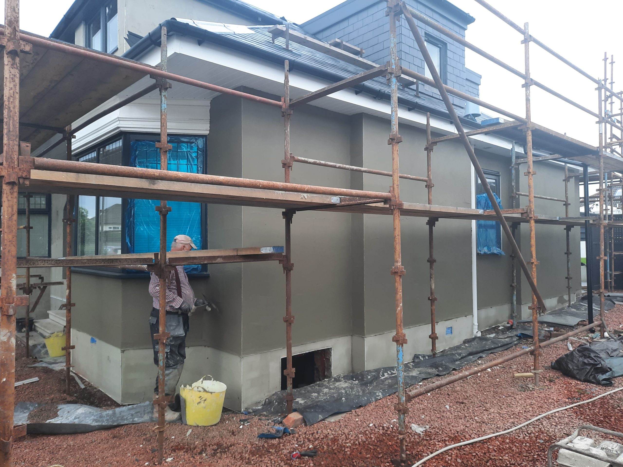 roughcast repair on side elevation with blue-covered windows