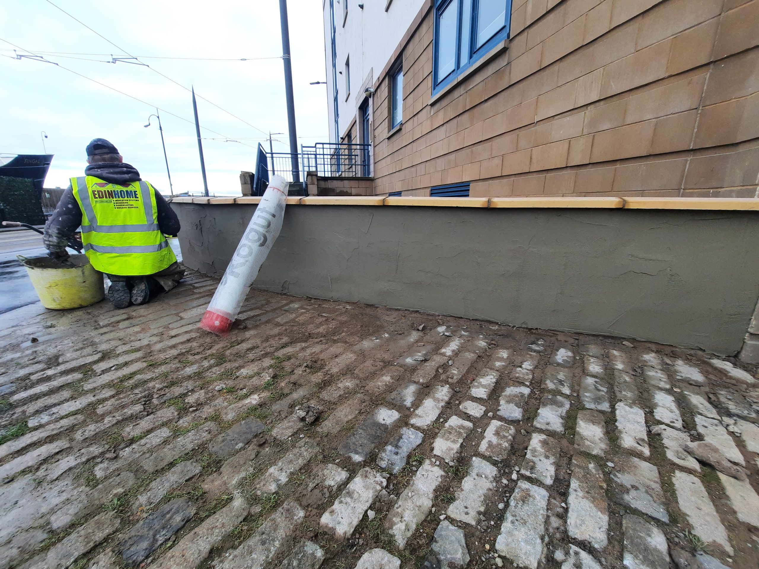 roughcasting Edinburgh applied on low boundary wall beside cobblestones