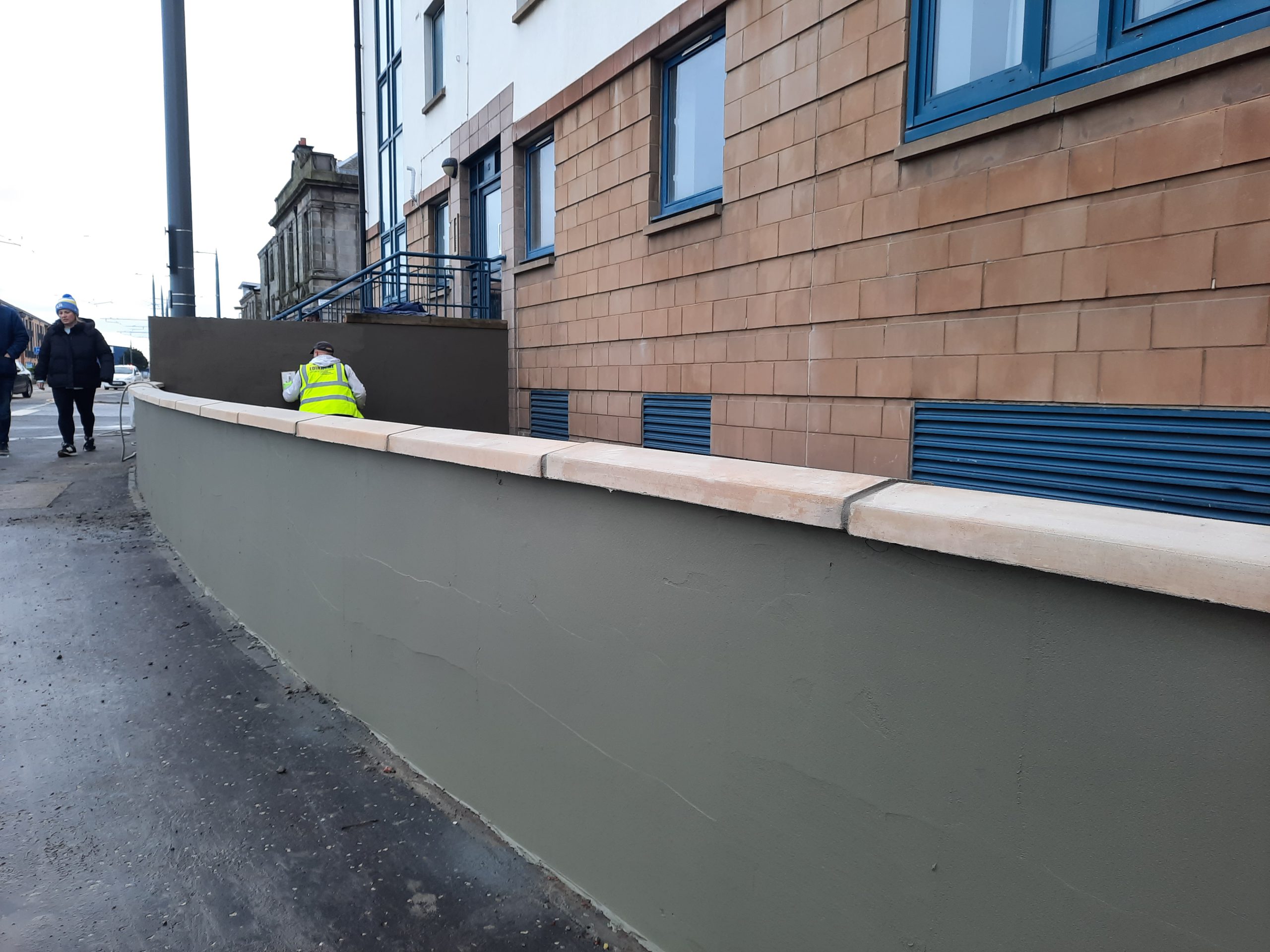 roughcast render repair on long low boundary wall