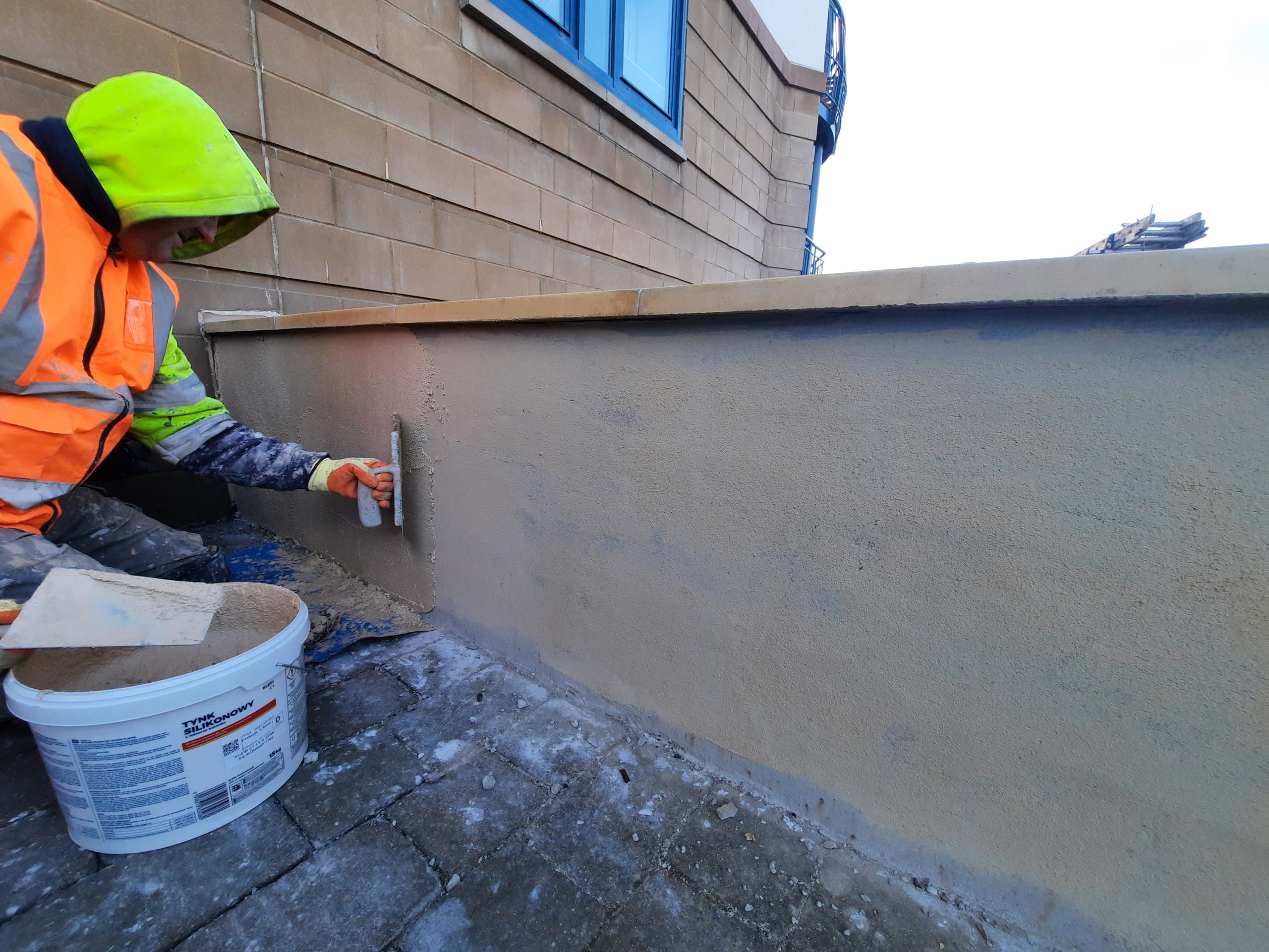 roughcast repair in progress on garden wall with coping stones
