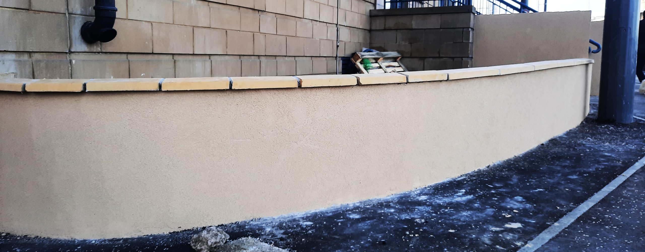 roughcast render repair along flat-topped boundary wall