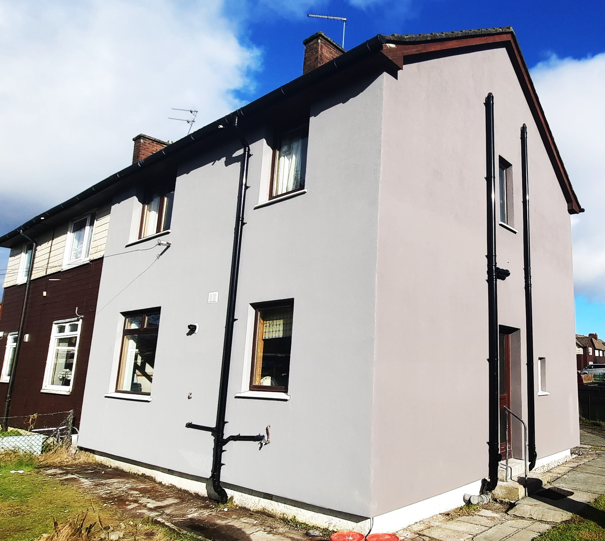 roughcast repair applied to two-storey house with side pipe