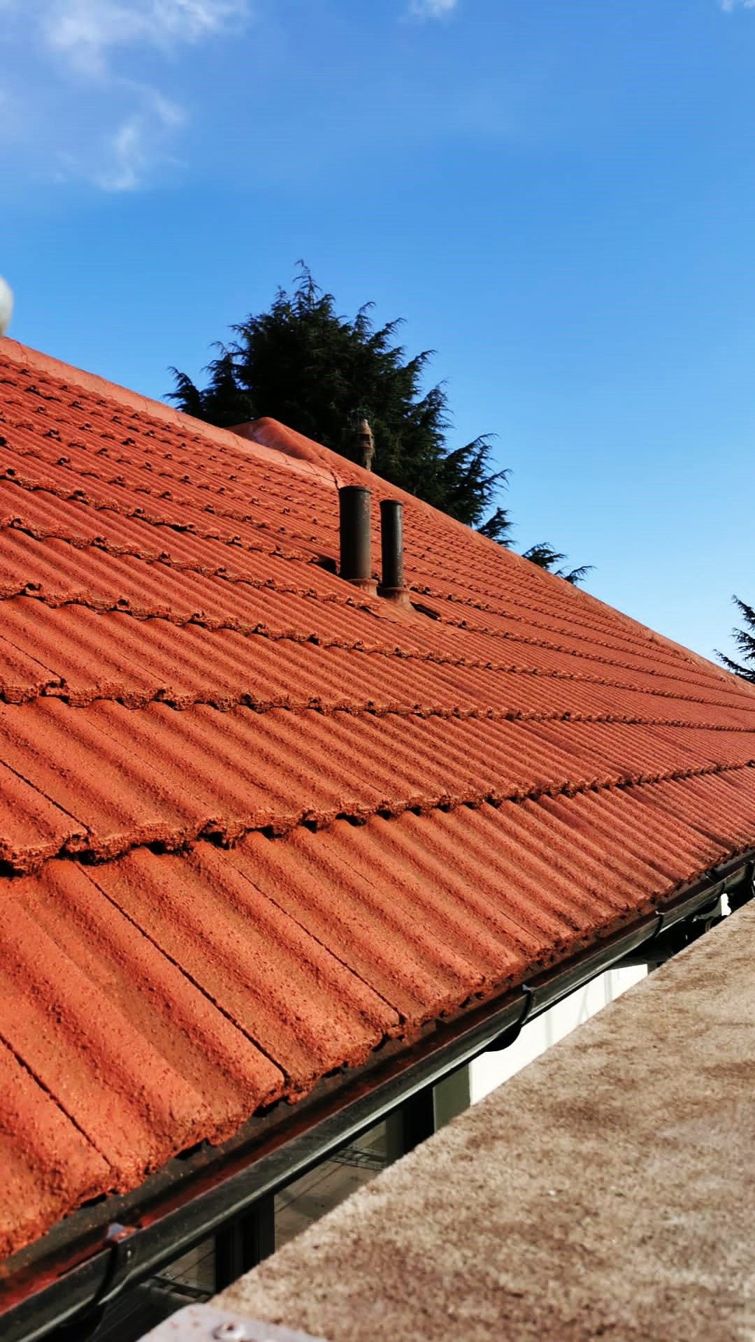 roughcast render repair under roof eaves above dark-framed window