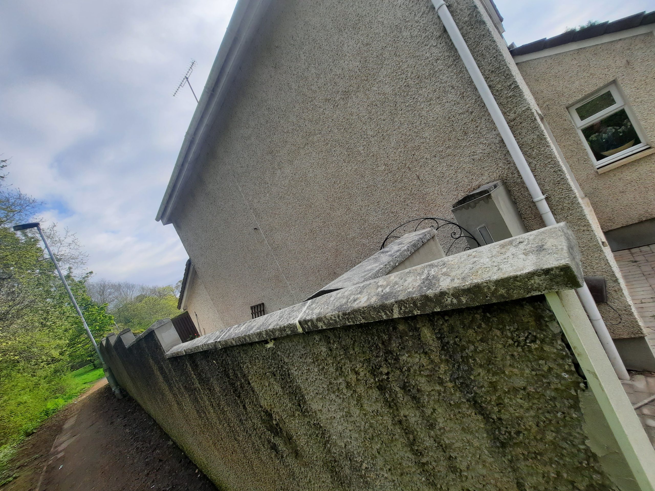 roughcast repair on moss-covered side wall