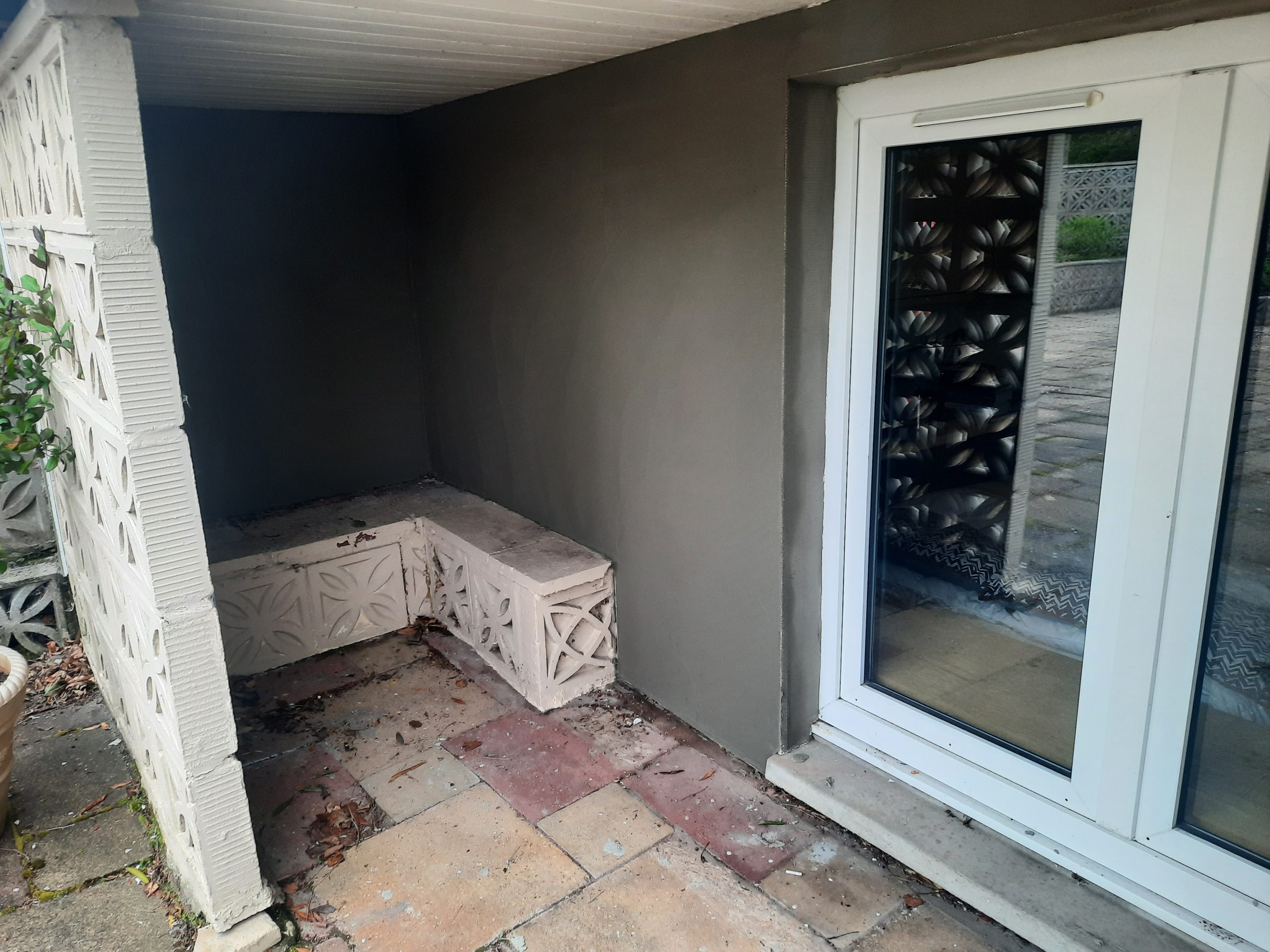 roughcasting Edinburgh on shaded patio wall beside glass door