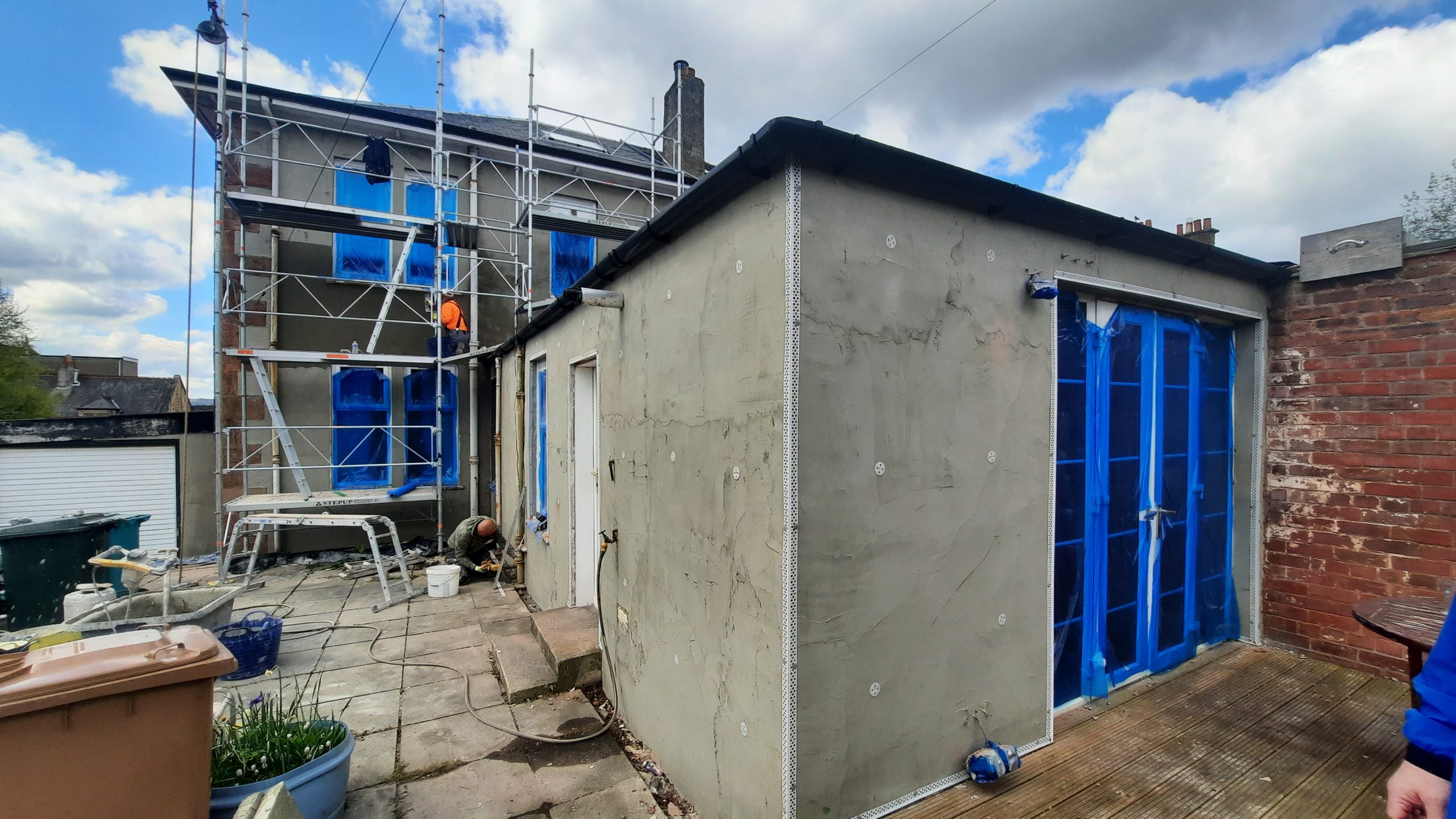 roughcast render repair on small outbuilding beside main house