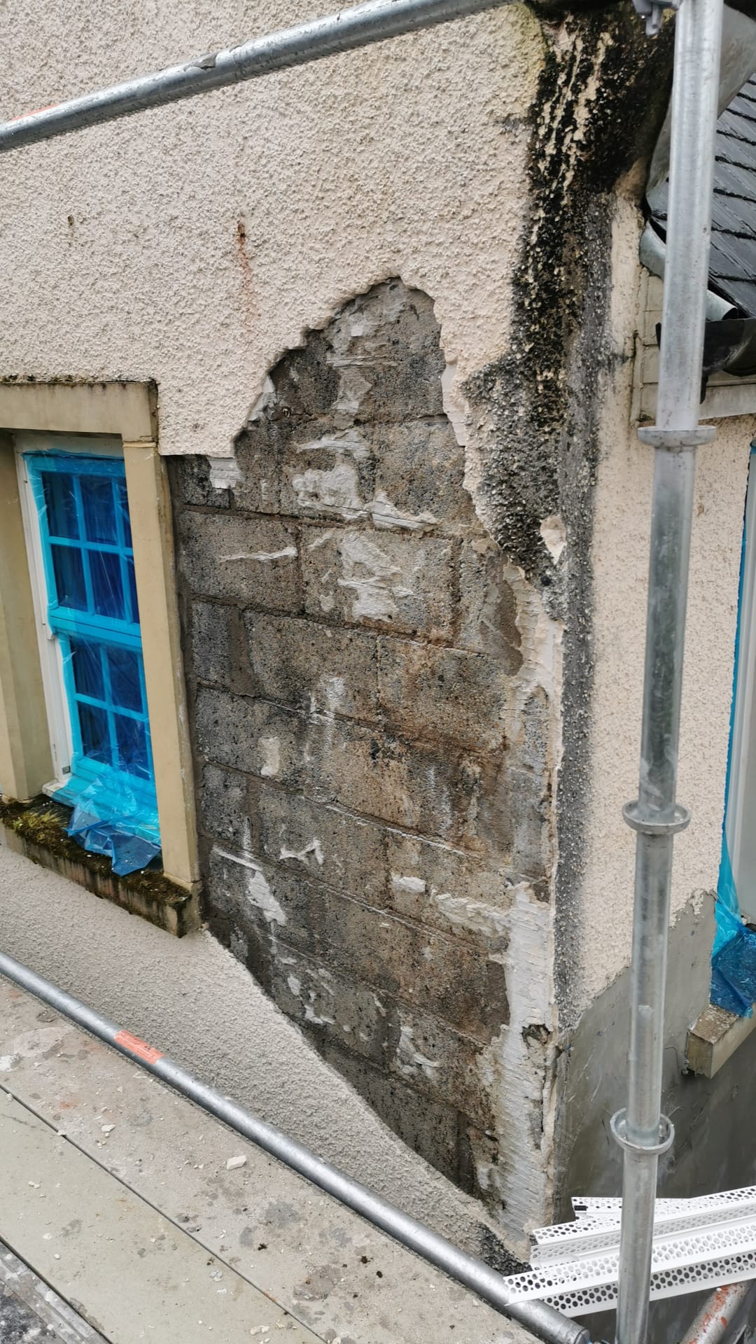 roughcaster Edinburgh repairing damaged wall beside blue window