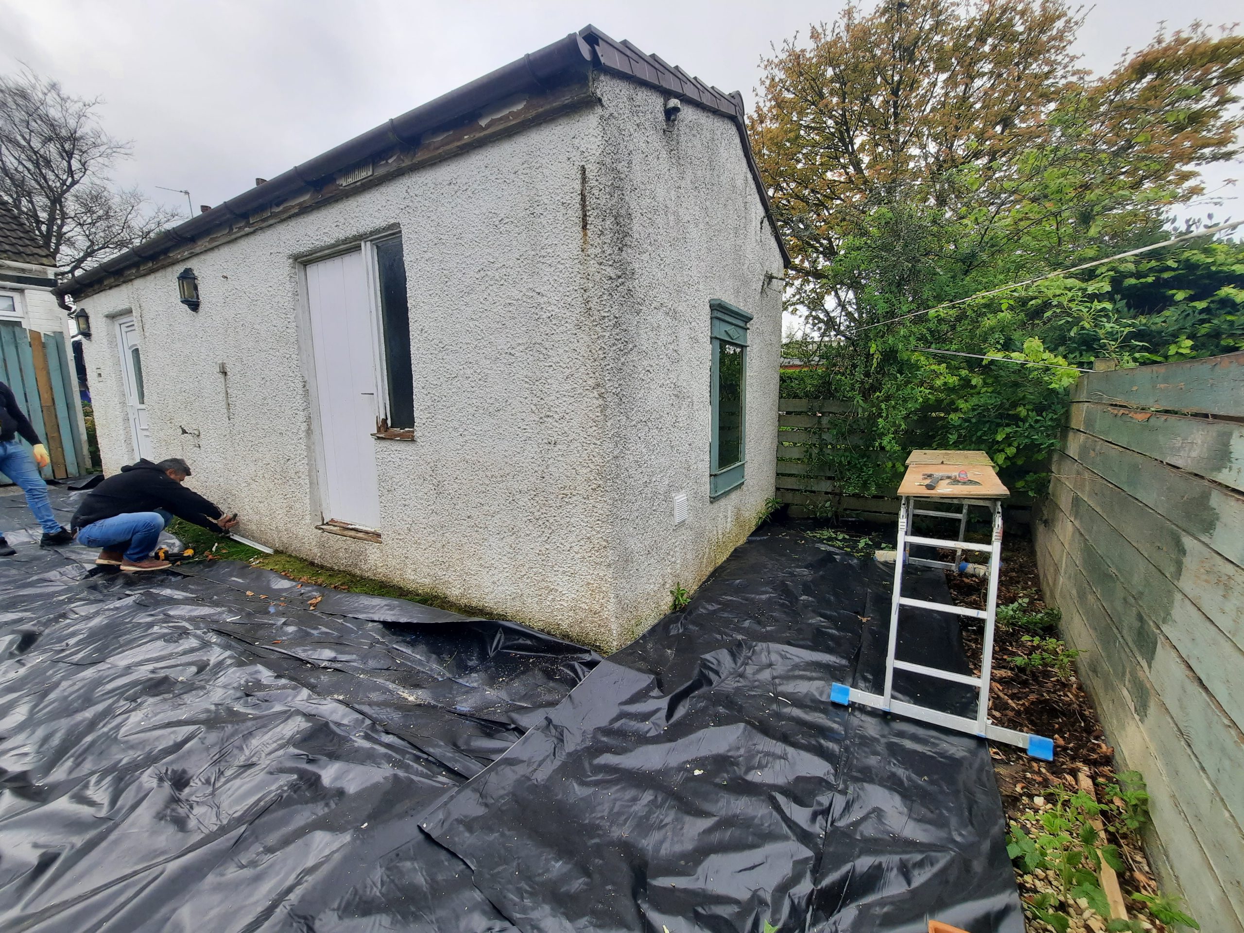 roughcast repair on outbuilding beside ladder