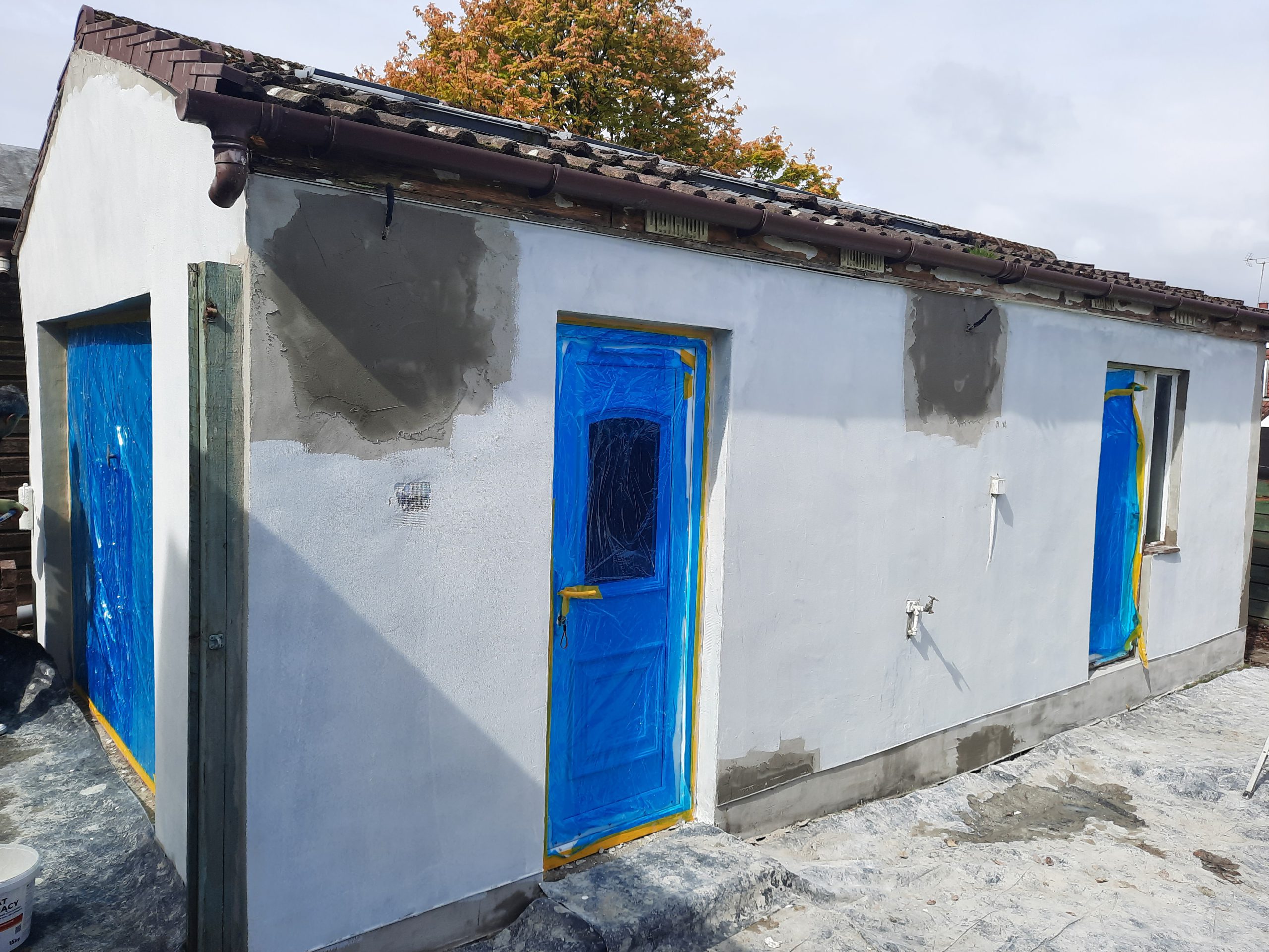 roughcast render repair around blue-covered door