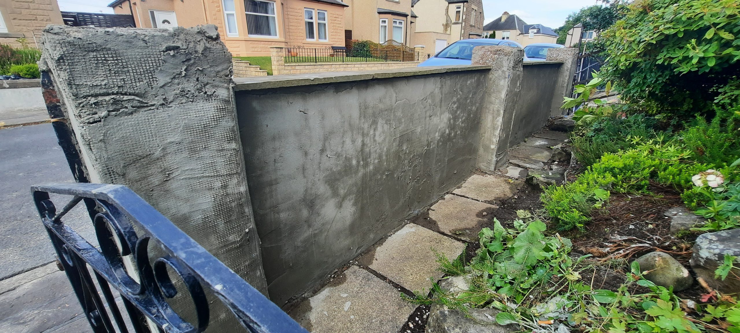 roughcaster Edinburgh working on narrow boundary wall