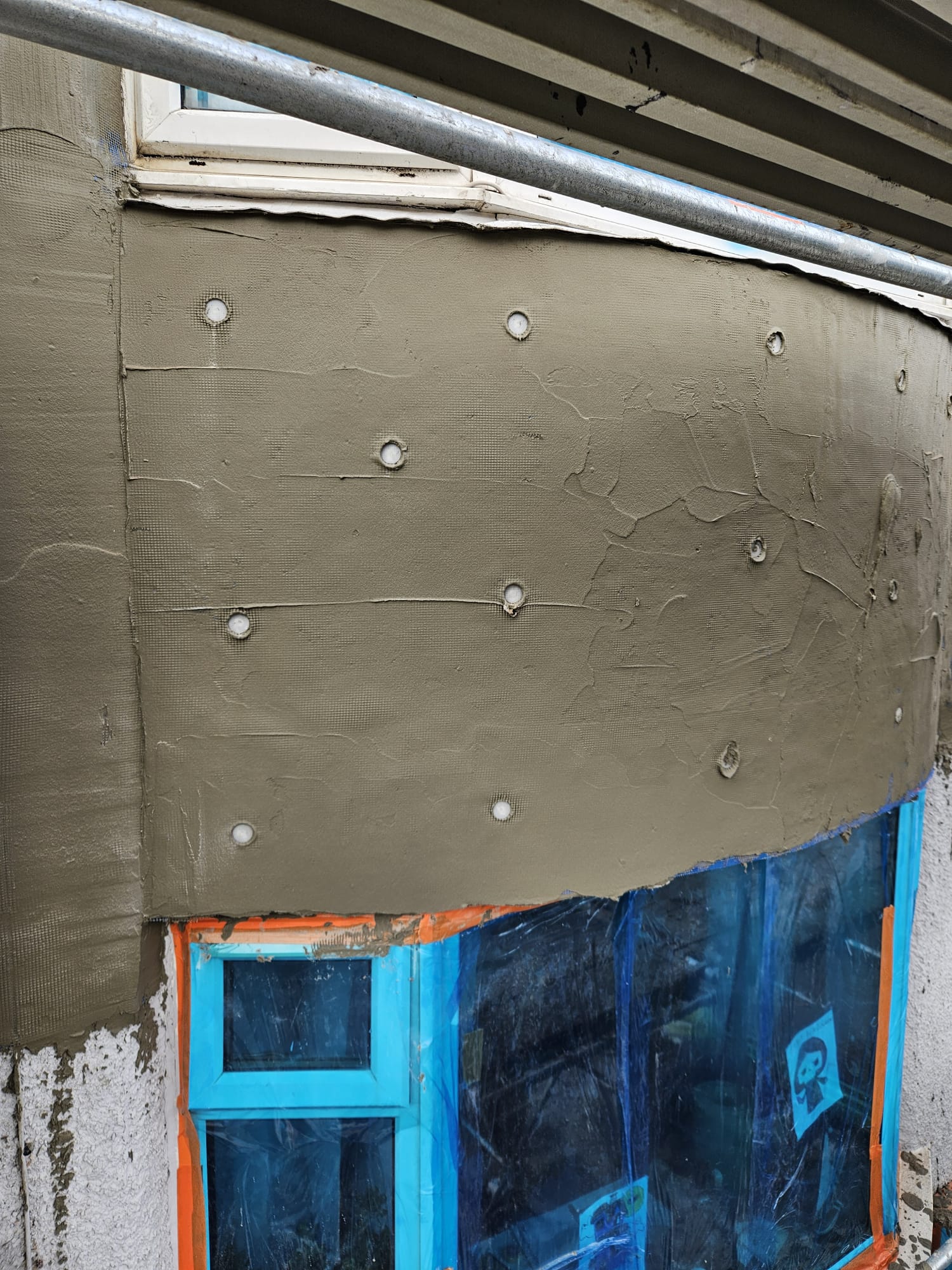 roughcast render Edinburgh on wall with visible fixing plugs