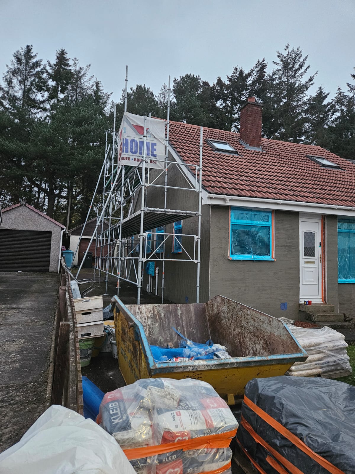 roughcast render repair in progress with blue window covers