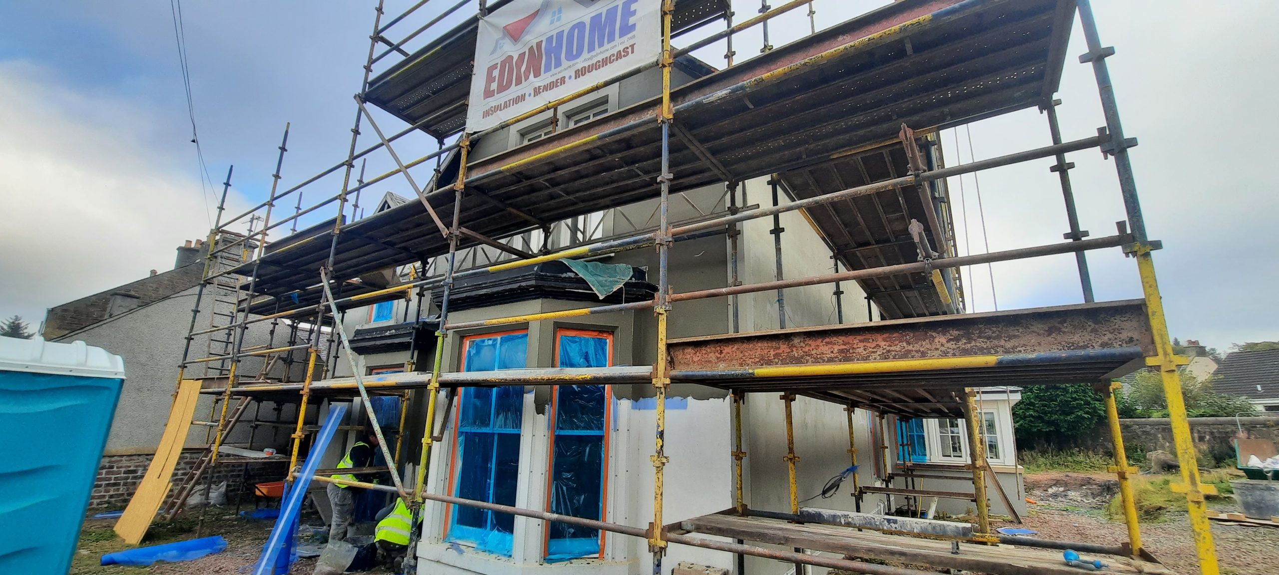 roughcast render repair on wall with blue window masking