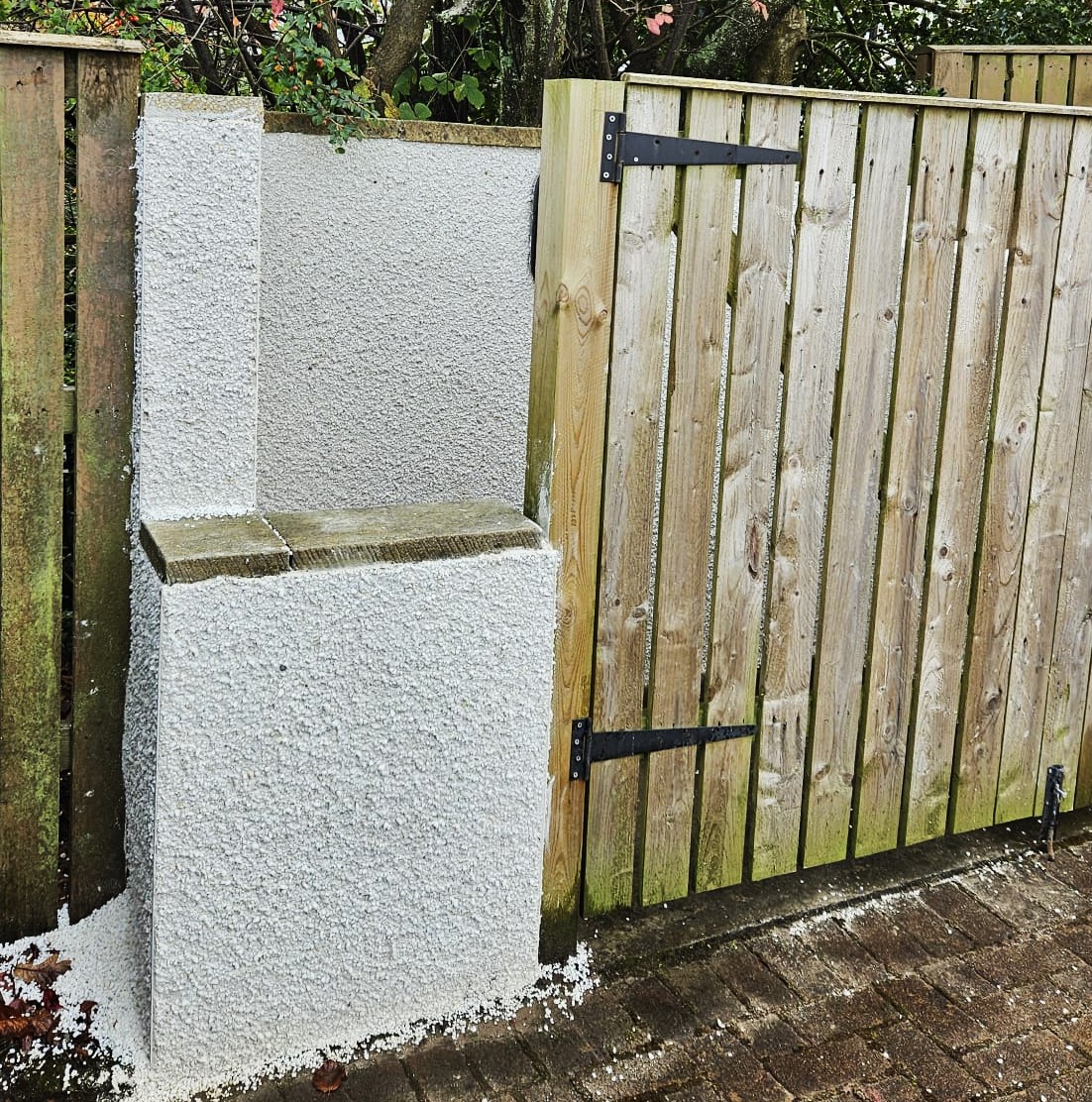 roughcast repair on outdoor wall beside wooden gate