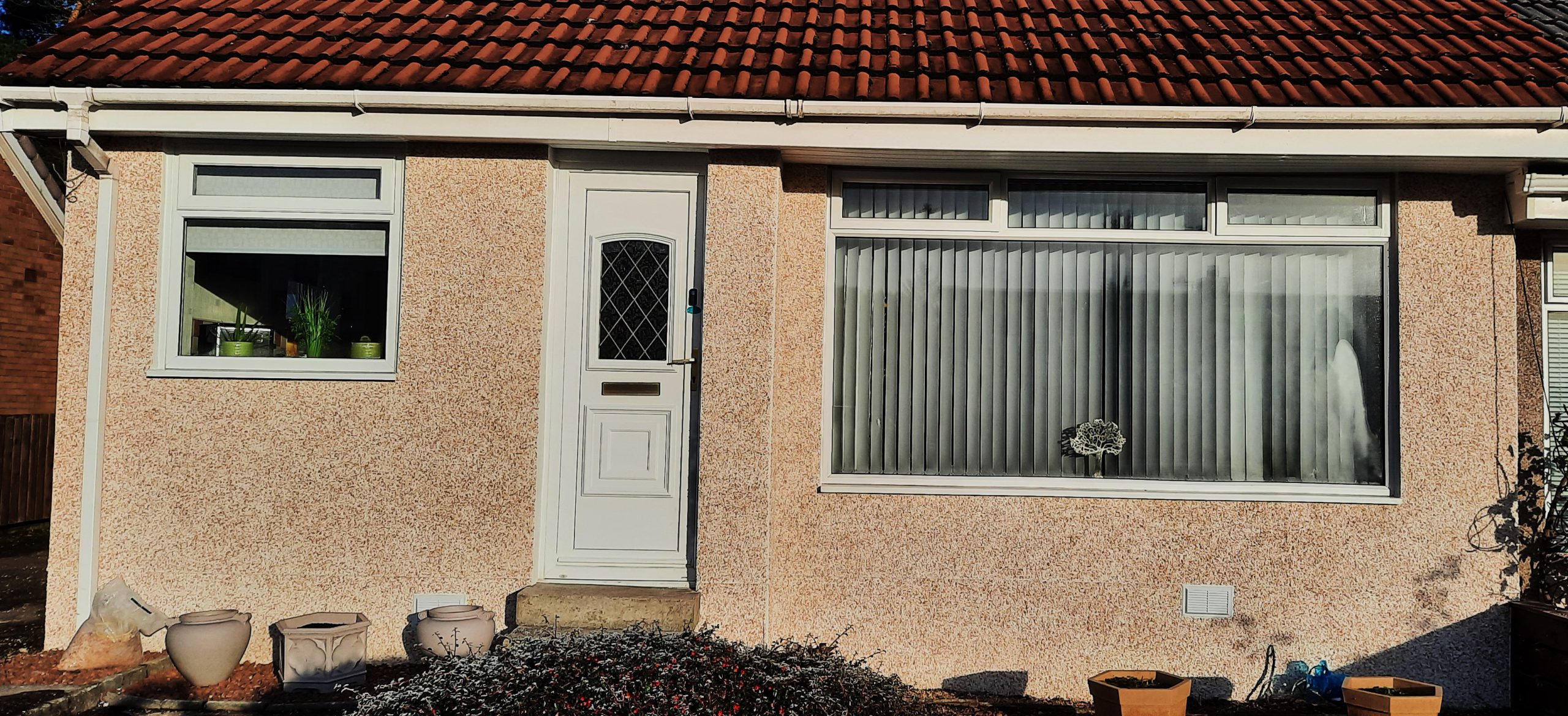 roughcast render repair on single-storey with white trim
